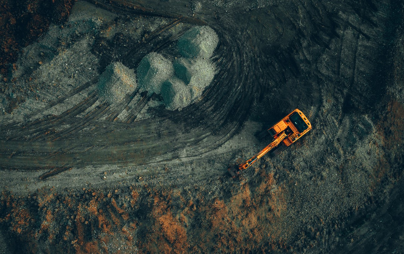 bright excavator at work on a dark background view from a drone.